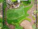 Aerial view of a meticulously landscaped backyard with a patio, firepit, garden beds, and expansive green lawn at 725 Heathland Dr, Roswell, GA 30075