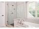 Bathroom featuring a glass shower, soaking tub, and lots of natural light at 725 Heathland Dr, Roswell, GA 30075