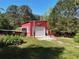 A red metal outbuilding with white trim, a garage door, and natural landscaping at 5618 Highway 212, Covington, GA 30016