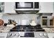 Close-up of a modern stainless steel gas range with granite countertops and white backsplash at 3820 Pheasant Run Trce, Cumming, GA 30028