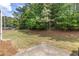 A view of the grassy backyard with mature trees and a concrete patio in the corner at 2033 Millstream Holw, Conyers, GA 30012