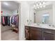 Bathroom vanity featuring dark cabinetry, white countertops, a large mirror, and a glimpse into a walk-in closet at 2033 Millstream Holw, Conyers, GA 30012