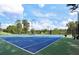 Well-maintained community tennis court with vibrant blue surface, surrounded by lush greenery and equipped with lighting for evening play at 53 Monet Nw Ct, Atlanta, GA 30327