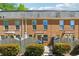 Brick townhome featuring manicured landscaping, fence, and welcoming entry at 135 N North River Dr, Atlanta, GA 30350