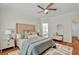 Stylish bedroom featuring a tufted headboard, modern ceiling fan, ensuite bathroom access, and hardwood flooring at 229 Brookview Pl, Woodstock, GA 30188