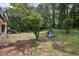 Expansive backyard featuring mature trees and a playset with a slide and swings at 4261 Vineyard Trl, Snellville, GA 30039