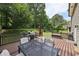 A deck with a metal table, chairs, grill and umbrella overlooks a large green backyard at 4261 Vineyard Trl, Snellville, GA 30039