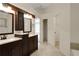 Modern bathroom featuring double vanity, wood cabinetry, tile floors, and entry to large closet at 5320 Taylor Rd, Alpharetta, GA 30022