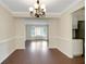 Dining room with sleek hardwood floors, modern lighting fixture, and an open doorway to a bay window-lit living area at 5320 Taylor Rd, Alpharetta, GA 30022