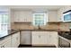 Well-lit kitchen with stainless steel appliances, dark countertops, and white cabinets at 5320 Taylor Rd, Alpharetta, GA 30022