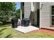 Small backyard with patio, gas grill, trash cans and green grass surrounded by trees at 2412 Wingfield Dr, Austell, GA 30106