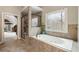 Bright bathroom featuring a soaking tub with jets, and an adjacent glass-enclosed shower at 2660 Burnt Hickory Dr, Cumming, GA 30028