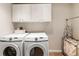 This laundry room features a modern washer and dryer and overhead white cabinets at 2660 Burnt Hickory Dr, Cumming, GA 30028