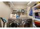 Spacious laundry room with modern washer and dryer units, storage shelves and utility sink at 6637 Oak Farm Se Dr, Acworth, GA 30102