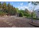 Spacious backyard with mature trees, a pergola-covered seating area, and decorative rock features at 3302 Anna Ruby Ln, Buford, GA 30519