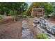 Landscaped backyard featuring a stone staircase leading to a pergola and a rock waterfall at 3302 Anna Ruby Ln, Buford, GA 30519