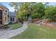Beautifully landscaped backyard with stone pathway leading to an outdoor fireplace and seating area at 3302 Anna Ruby Ln, Buford, GA 30519
