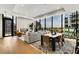 Elegant living room and dining area with hardwood floors, modern fireplace, city views from expansive windows at 40 12Th Ne St # 1406, Atlanta, GA 30309