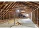 Unfinished attic space with exposed wood beams and some natural light through a window at 4708 Tall Pines Nw Dr, Atlanta, GA 30327