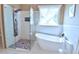 Bright bathroom featuring a soaking tub, tiled shower, pebble tile floor, and large window at 3740 Duckcove Way, Cumming, GA 30041