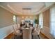 Elegant dining room with tray ceilings, wainscoting, and stylish lighting at 3740 Duckcove Way, Cumming, GA 30041