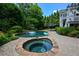 Backyard pool and spa with clear blue water, floats, stone pavers, lush landscaping, and deck at 3740 Duckcove Way, Cumming, GA 30041
