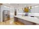 Bright kitchen with white cabinets, gold hardware, stainless steel refrigerator, large island, and hardwood floors at 3774 Eli Dr, Snellville, GA 30039