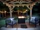 Backyard patio area with fire pit, cozy seating, string lights, and landscaping at 492 Thorn Creek Way, Dallas, GA 30157