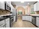 Bright kitchen with stainless steel appliances, white cabinets, and black countertops, seamlessly connecting to the dining area at 492 Thorn Creek Way, Dallas, GA 30157