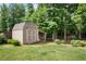 A storage shed sits on a grassy lawn next to a wooded area, providing extra space for tools and equipment at 492 Thorn Creek Way, Dallas, GA 30157