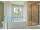 Bathroom featuring a soaking tub with window and glass enclosed shower with marble-look tile at 9183 Golfview Cir, Covington, GA 30014