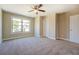 Spacious bedroom featuring plush carpeting, a ceiling fan, and a large window with a view of the outdoors at 9183 Golfview Cir, Covington, GA 30014
