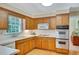 Traditional eat-in kitchen with wood cabinets, white appliances, and a window overlooking the yard at 3999 Saint Clair Ne Ct, Brookhaven, GA 30319