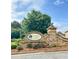 Stone entrance sign for 'Whispering Lake' community amidst lush landscaping and mature trees at 6140 Stillwood Ln, Cumming, GA 30041