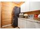 Bright laundry room features a stacked washer and dryer, white cabinets, and granite countertops at 6140 Stillwood Ln, Cumming, GA 30041