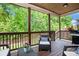 Relaxing outdoor porch with comfortable seating, a grill, a wood deck and tree-lined backyard at 6140 Stillwood Ln, Cumming, GA 30041