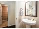 Cozy powder room with pedestal sink, decorative mirror, and access to the laundry room at 6140 Stillwood Ln, Cumming, GA 30041