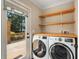 Functional laundry room with modern washer and dryer, butcher block countertop, shelving, and door to the outside deck at 166 Martha Ave, Atlanta, GA 30317