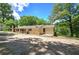 Single-story home with a gravel driveway and surrounded by lush trees and blue skies at 191 White Oak Church Rd, Dallas, GA 30157