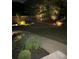 Backyard landscaping featuring a stone retaining wall, lush lawn, and mature trees, illuminated at night at 2258 Bright Water Dr, Snellville, GA 30078