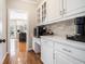 Bright butler's pantry features white cabinets, stone backsplash, and marble countertops with modern coffee appliance at 2258 Bright Water Dr, Snellville, GA 30078