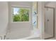 Relaxing bathroom showcasing a soaking tub, a glass-enclosed shower, and a window with a peaceful treetop view at 82 Hydrangea Cir, Fairburn, GA 30213