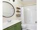 Stylish bathroom with a green vanity, round mirror, and shower-tub combination at 6505 Hampton Creek Dr, Cumming, GA 30041