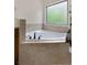 Bathroom featuring a corner soaking tub with tile surround and a window at 117 Constance Dr, Locust Grove, GA 30248