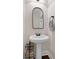 This bathroom features a pedestal sink, mirror, and wood floors at 117 Constance Dr, Locust Grove, GA 30248