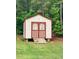 Charming storage shed with red trim, double doors, and a wooden ramp at 117 Constance Dr, Locust Grove, GA 30248