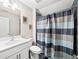 Bathroom featuring a single sink vanity, decorative wall art, and a shower with a stylish blue striped curtain at 410 Gardens Of Harmony Dr, Canton, GA 30115