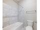 Well-lit bathroom with a white tiled shower-tub combination, toilet, and a neutral color palette at 4905 Sterling Close, Buford, GA 30518