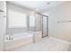 Bright bathroom featuring a tub and a separate glass shower with neutral tile and flooring at 4905 Sterling Close, Buford, GA 30518