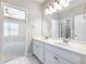 Bright bathroom featuring a double vanity with white cabinetry and a large mirror reflecting an open doorway to a bedroom at 4905 Sterling Close, Buford, GA 30518